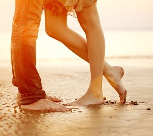רגליהם של גבר ואישה הפונים זה לעבר זה בחוף הים